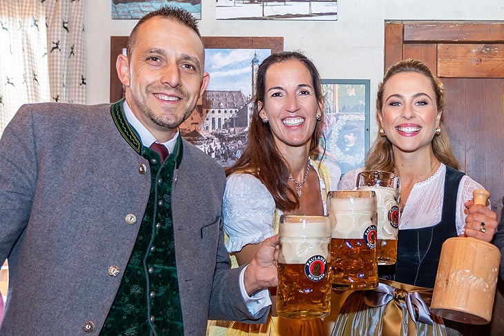 Prost – mit der ersten Mass Wiesnbier! (v.l.) Die Wirte Alex Egger und Kathrin Wickenhäuser-Egger mit Anzapferin und Rennfahrerin Sophia Flörsch (©Foto: Simone Naumann)